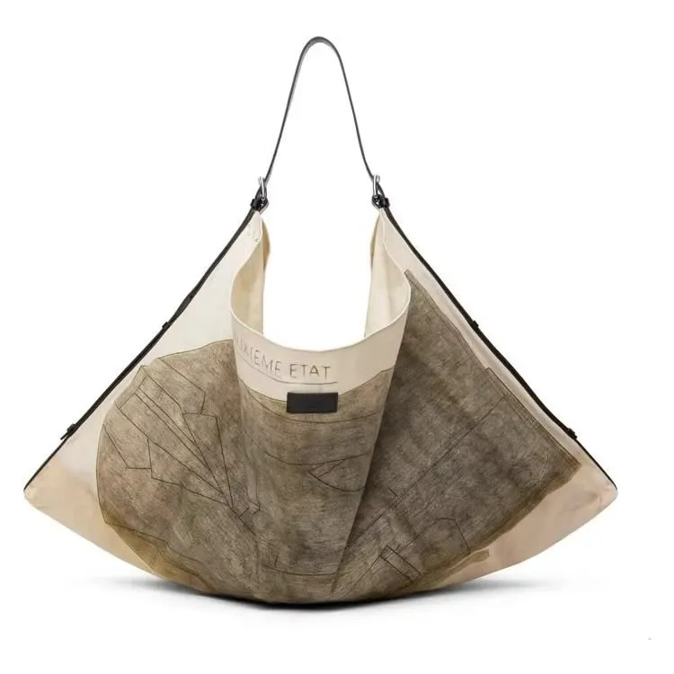 Wide cream canvas tote with a faded map print and a black leather strap